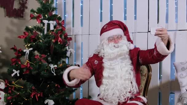 Santa Claus Is Sit and Make Selfi His Smartphone, Room with Fireplace and Christmas Tree, Gifts. - Filmagem, Vídeo