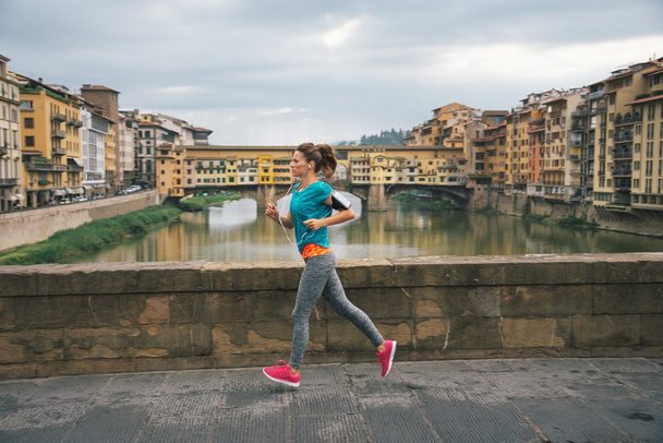 Young female jogger with headset is running by Arno riverside - Foto, Bild