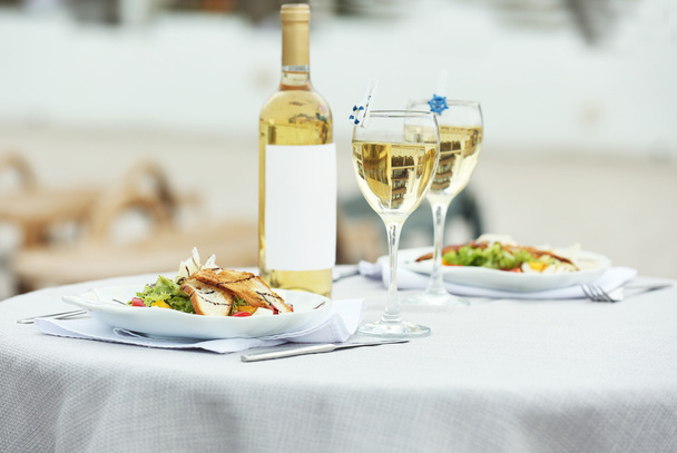 Salade savoureuse avec vin sur table blanche
 - Photo, image