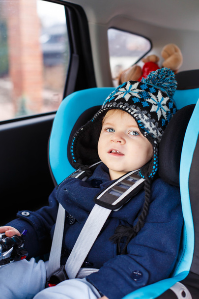 Adorable toddler boy sitting in safety car seat  - 写真・画像