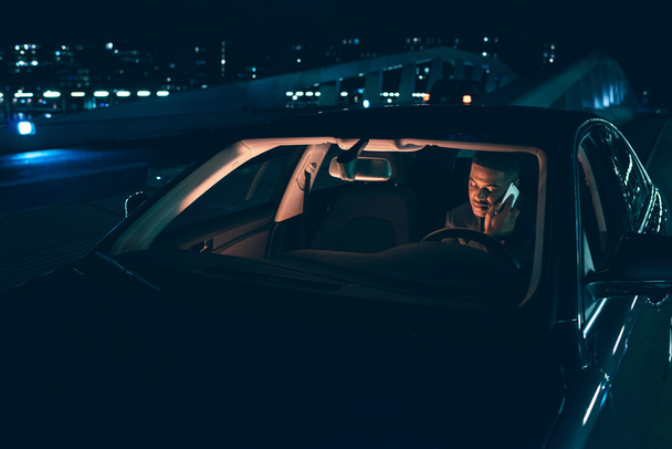 Ο άνθρωπος χρησιμοποιεί κινητό τηλέφωνο στο αυτοκίνητο τη νύχτα - Φωτογραφία, εικόνα
