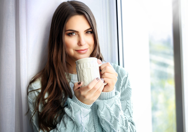 Bella donna seduta sul bordo della finestra con una tazza di caffè
 - Foto, immagini