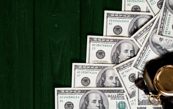 Стек грошей доларів, викладених як драбина з антикварними золотими годинниками на темно-зеленому ретро стилізованому дерев'яному фоні
 - Фото, зображення