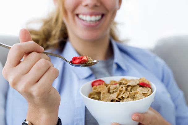 Beautiful young woman eating cereals at home. - Foto, Bild