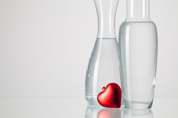 Two vases with clean water and red heart   - Foto, afbeelding