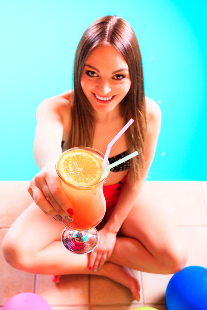 Happy woman with balloons and cocktail at poolside - 写真・画像