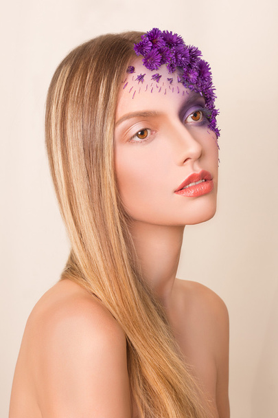 Μόδα μοντέλο με μεγάλο hairstyle και λουλούδια στο πρόσωπό της. - Φωτογραφία, εικόνα