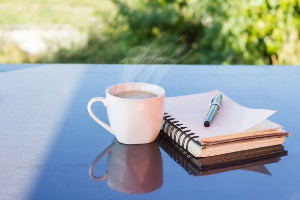 Классическая белая чашка черного кофе, украшенная запиской и ручкой на зеленом природном фоне
 - Фото, изображение