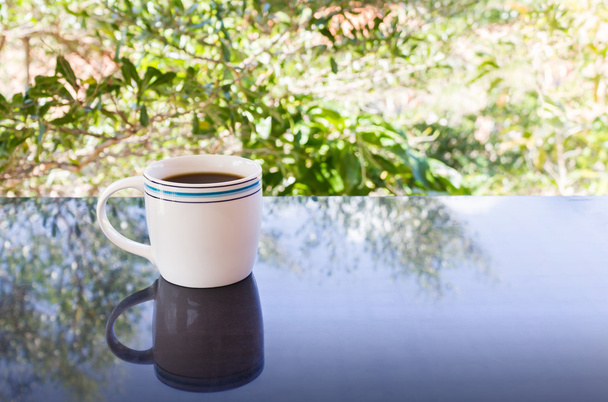 Taza blanca clásica de café negro con fondo de árbol
 - Foto, imagen