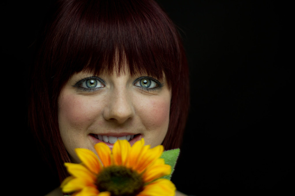 Mädchen lächelt hinter Sonnenblume - Foto, Bild