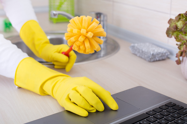Multitasking concept. Woman with cleaning brush and laptop - Photo, Image