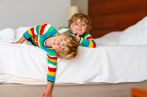 Два маленьких мальчика-близнеца развлекаются в постели после сна
 - Фото, изображение