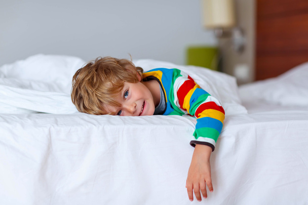 Adorable kid boy after sleeping in his white bed with toy - Фото, зображення