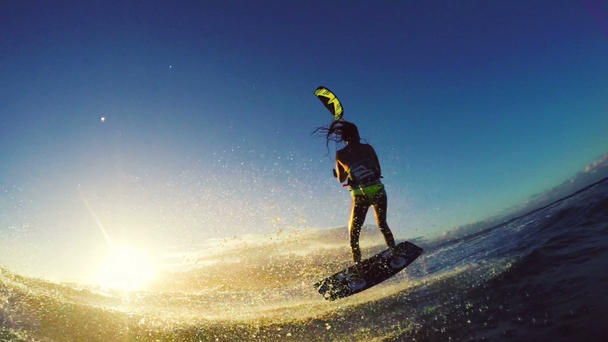 女の子カイトサーフィンは、日没でビキニ極端なカイトサーフィンで海の波の上に空気をキャッチ. - 映像、動画