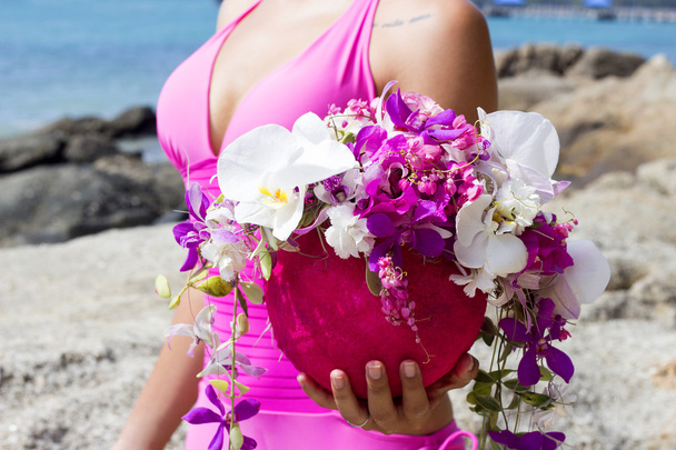 Close up portrait bouquet beautiful flowers in arms of woman wearing pink swimsuit. Phuket island, Thailand - Zdjęcie, obraz