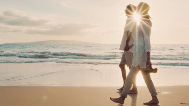 Sunset Walk em uma praia de luxo. Casal mais velho segura as mãos e caminha pela praia ao pôr do sol ficando com os pés molhados
 - Filmagem, Vídeo
