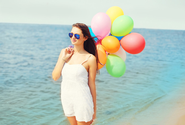 Happy young woman with colorful balloons on beach near sea enjoy - Фото, зображення