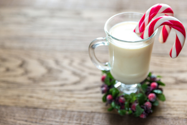 A glass of eggnog with candy cane - Photo, Image