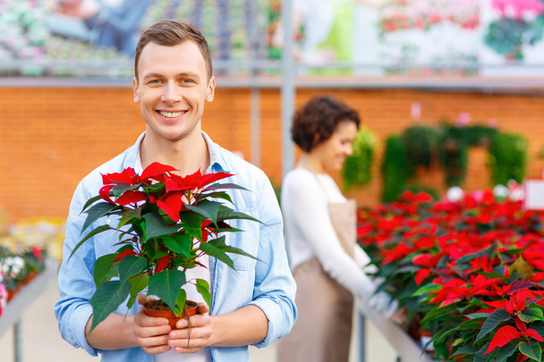 Delighted customer holding a flower. - Φωτογραφία, εικόνα