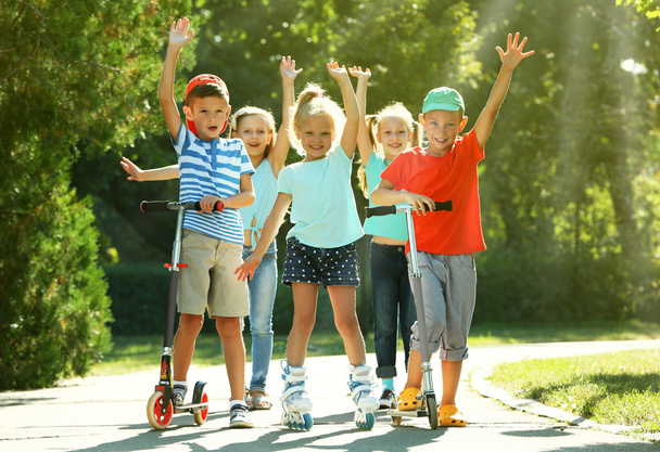 Children riding on scooters and roller skates - Fotó, kép