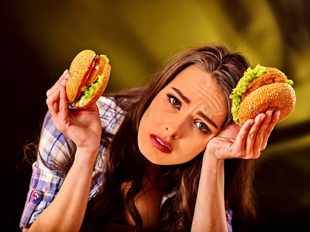 Verärgertes Mädchen hält Hamburger in der Hand - Foto, Bild