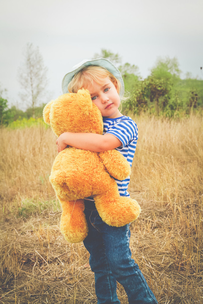 Schattig klein meisje knuffelen een grote teddybeer - Foto, afbeelding