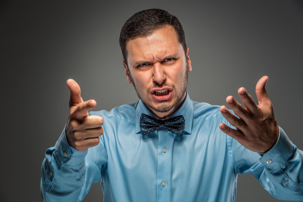 Muotokuva vihainen järkyttynyt nuori mies sinisessä paidassa, perhonen solmio
 - Valokuva, kuva