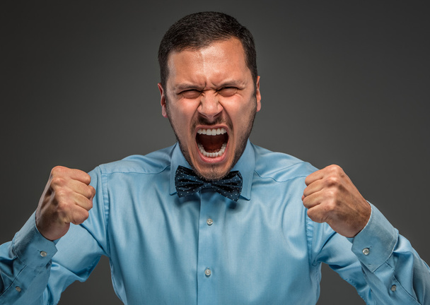 Portrait angry upset young man in blue shirt, butterfly tie - 写真・画像