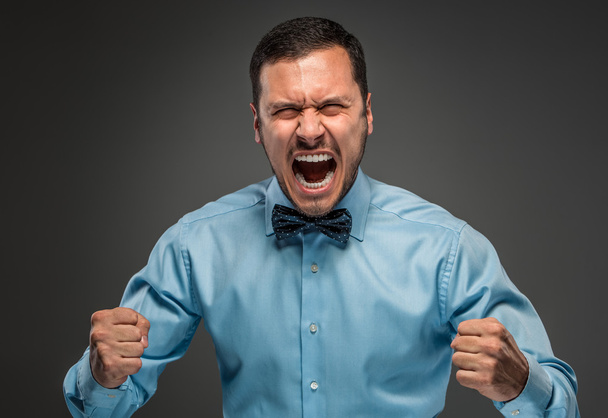 Portre kızgın genç adam mavi gömlekli, kelebek kravat üzgün - Fotoğraf, Görsel