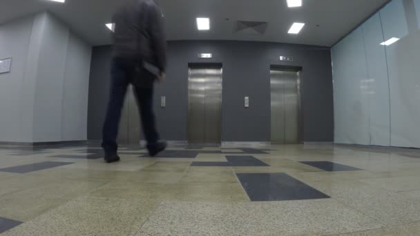 Młody człowiek czekać na windę, kiedy nadejdzie. Szeroki widok, nagrany z punktu widzenia niskiego - Materiał filmowy, wideo
