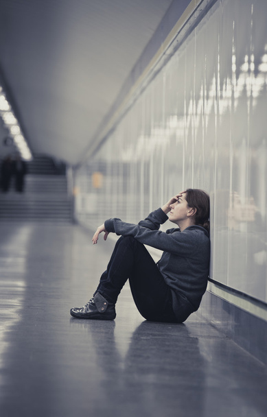young sad woman in pain alone and depressed at urban subway tunn - 写真・画像