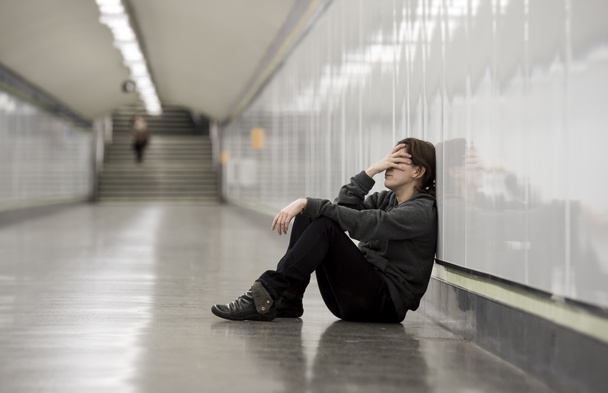 joven triste mujer en el dolor solo y deprimido en metro urbano túnel suelo preocupado sufrimiento depresión
 - Foto, Imagen