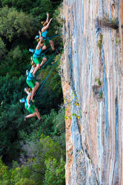 Žena horolezec klesá z vrcholu vysoké skalní stěny - Fotografie, Obrázek