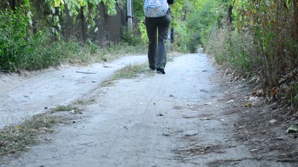 Nainen housuissa reppu kävelee pois kamerasta
 - Materiaali, video