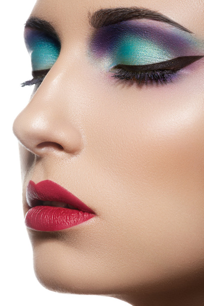 Closeup beauty portrait of attractive model face with bright visage. Multicolored eye makeup and vinous lips make-up - Fotó, kép