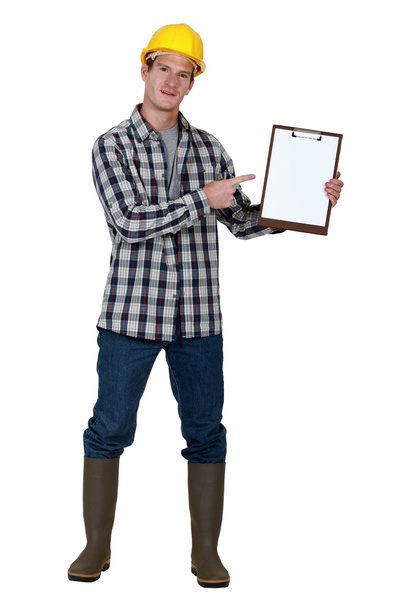 Construction worker pointing to a blank clipboard - Photo, image