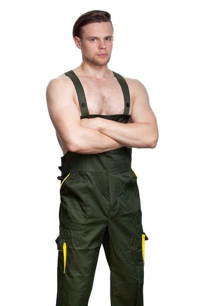 ein Mann mit nacktem Oberkörper in dunkelgrünen Overalls - Foto, Bild