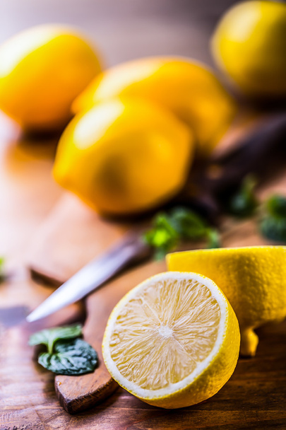 Lemons cut into the old kitchen board with mint leaves - 写真・画像