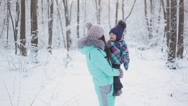 雪に覆われた冬の森で散歩に女の赤ちゃんを持って幸せな母 - 映像、動画