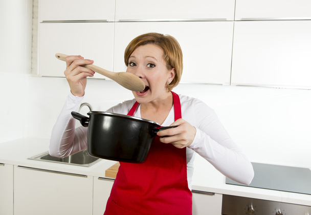 красива домашня кулінарна жінка на кухні тримає ложку і готує горщик дегустації смачного супу
 - Фото, зображення