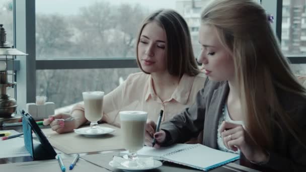 Dos niñas diseñadores discuten el proyecto utilizando tableta en la cafetería
 - Metraje, vídeo