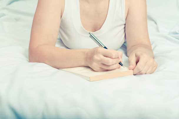 junge Frau mit Notizbuch im Bett.  - Foto, Bild