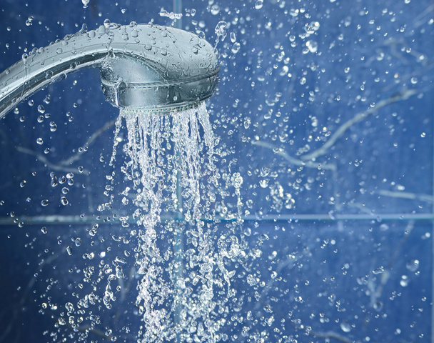 Shower on blue background with water drops fly in the air, image with space for text on the right - Zdjęcie, obraz