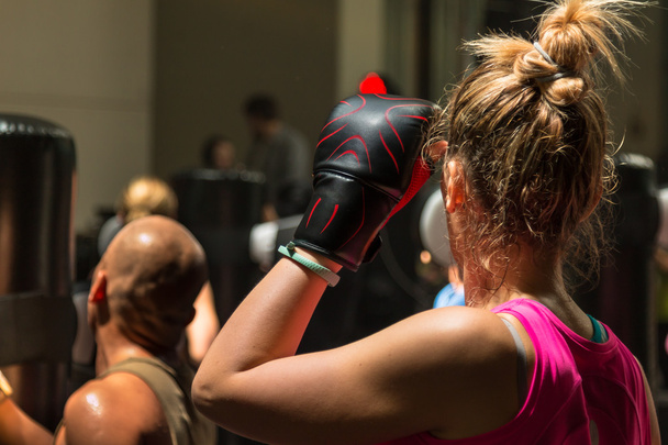 Молодая женщина в боксёрской перчатке в классе фитнеса
 - Фото, изображение