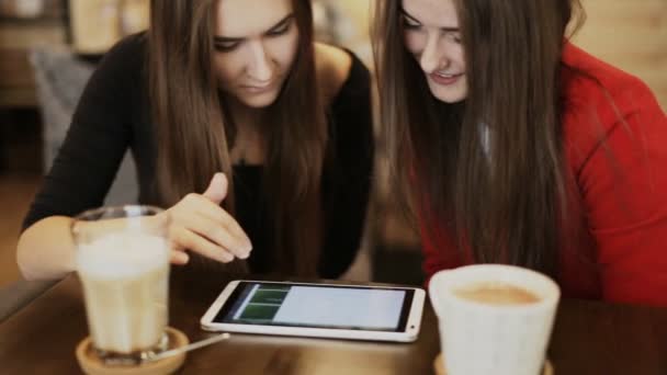 Two happy girlfriends with tablet smile in cafe - Video, Çekim