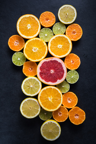 Цитрусовые наполовину срезанные фрукты на темном фоне
 - Фото, изображение
