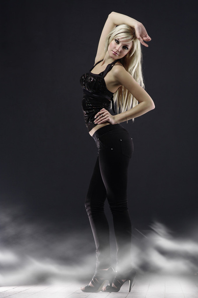 Caucasian blonde woman in full-length poses, dressed in black on a dark bac - Foto, Imagen