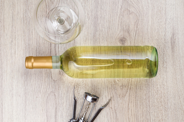 Wine bottle with corkscrew on wooden background - Fotó, kép