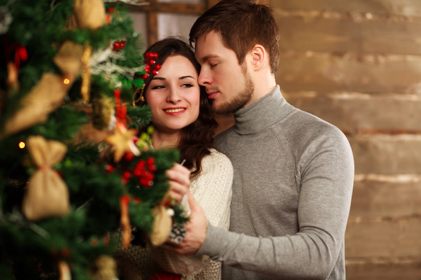 Young couple in love decorates a Christmas tree at home - Fotó, kép