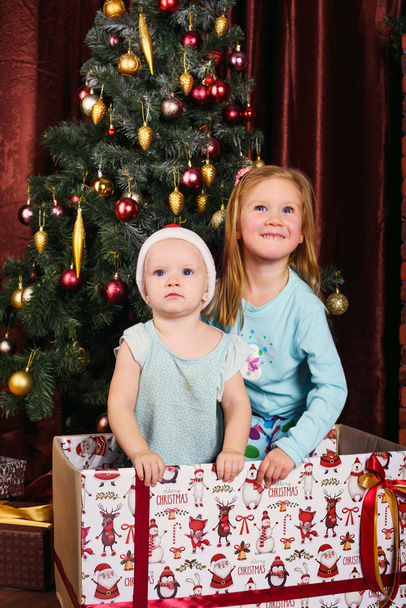 two little girls playing with presents in christmas decorations - Foto, imagen